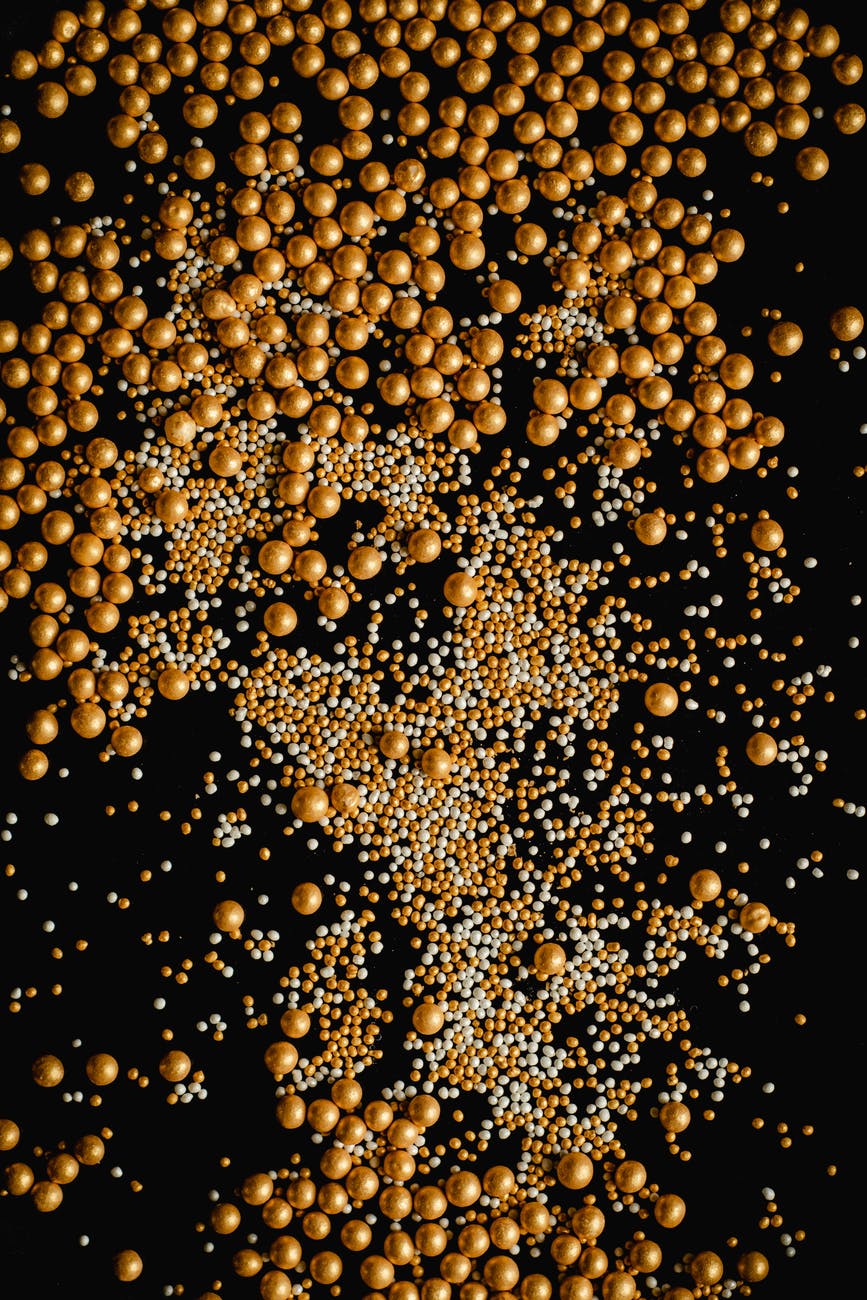 top view of golden and white pearls on a black surface